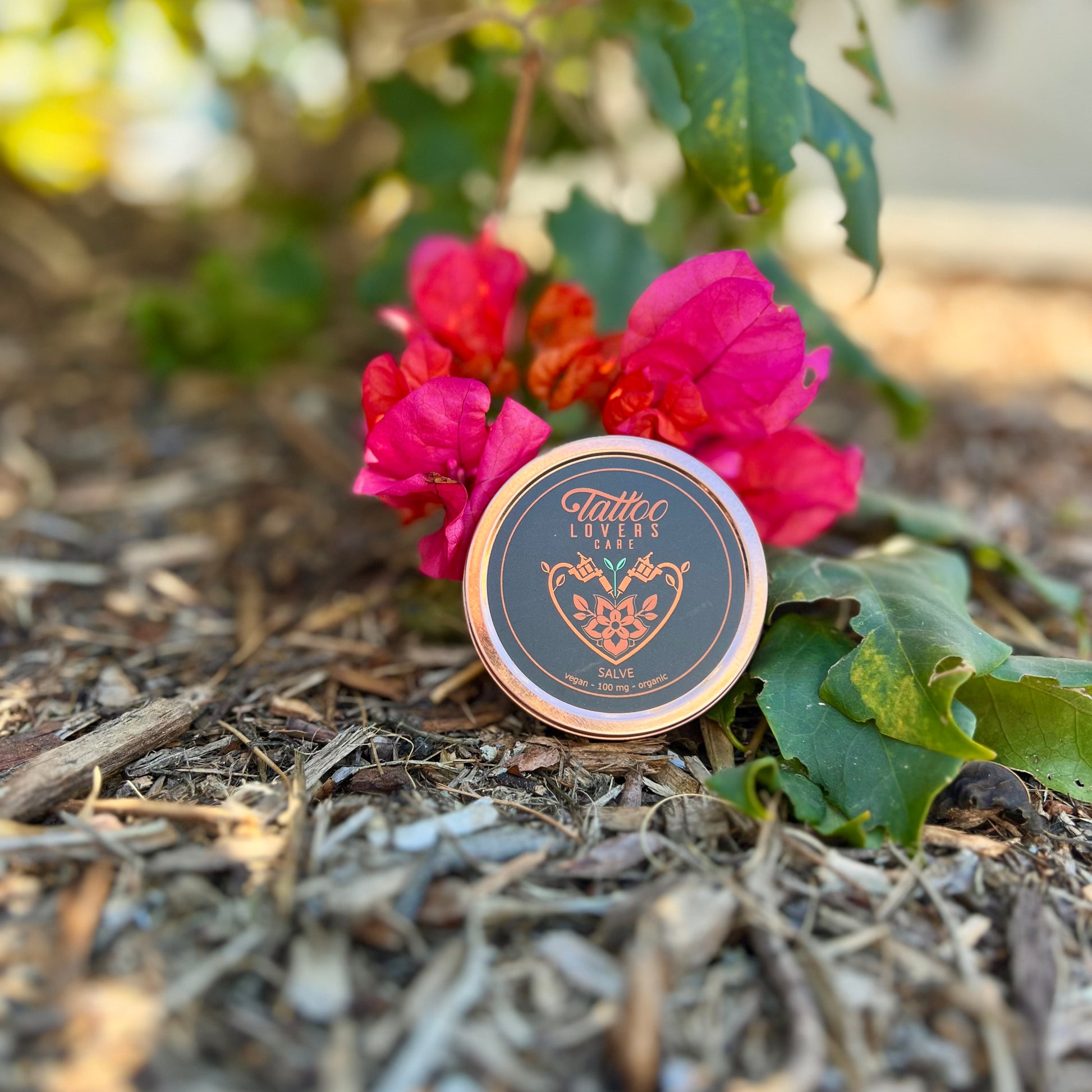 a container of tattoo lovers care salve with a pink flower in the display. 100% organic with CBD. Superior quality